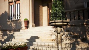 A stone statue with a planter on top, in front of a building with steps and a window. - Villa Tower Inn (Pisa)