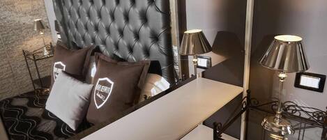 Une chambre à coucher moderne avec une tête de lit capitonnée, une table de chevet et deux lampes.