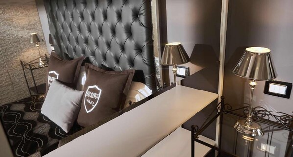 A modern bedroom with a tufted headboard, a bedside table, and two lamps.