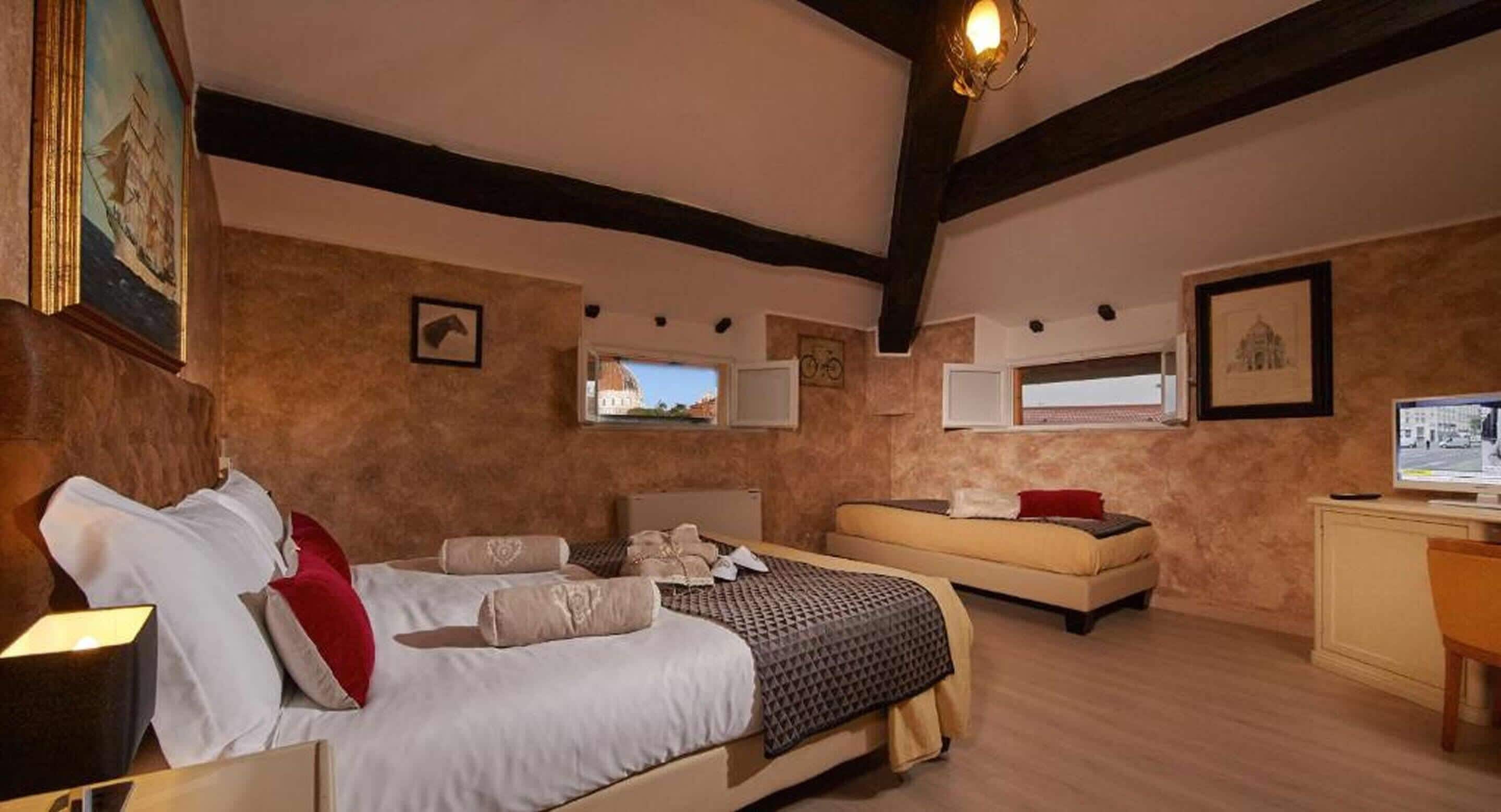 A bedroom with a large bed, a smaller sofa, a desk, and a computer.