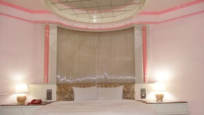 A hotel room with a large bed, two bedside tables with lamps, a telephone, and a decorative wall panel. - Modern Plaza Hotel (Kaohsiung)
