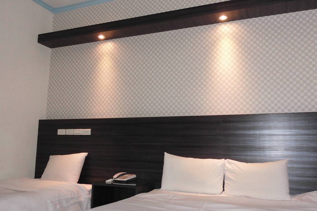 Una habitación de hotel con una cama grande, dos mesitas de noche y un cabecero.