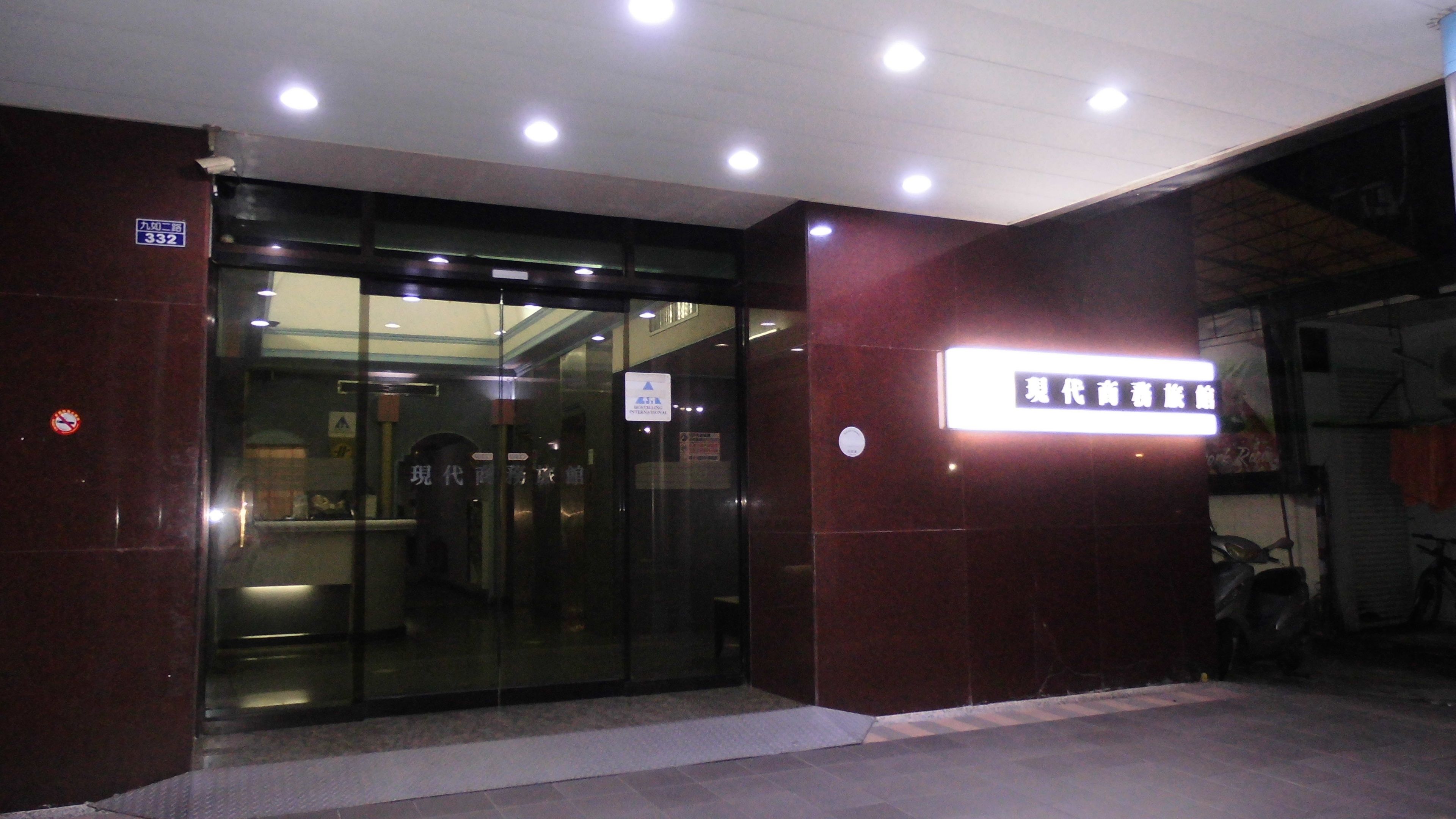 A building entrance with a glass door, a sign indicating '332', and a neon sign above the door.