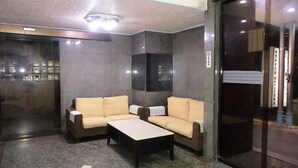 A modern lobby with a sofa set, a coffee table, and a glass partition with a sign. - Modern Plaza Hotel (Kaohsiung)