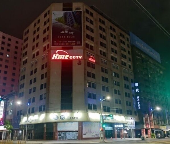 A multi-story hotel with a prominent 'Hime CCTV' sign on the facade, multiple windows, and a visible entrance with a sign for a 'Hotel'.