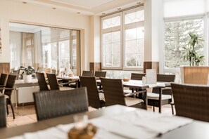 A dining area with tables and chairs, large windows, and a view of trees outside. - Parkhotel Weber-Müller (Bad Lauterberg)
