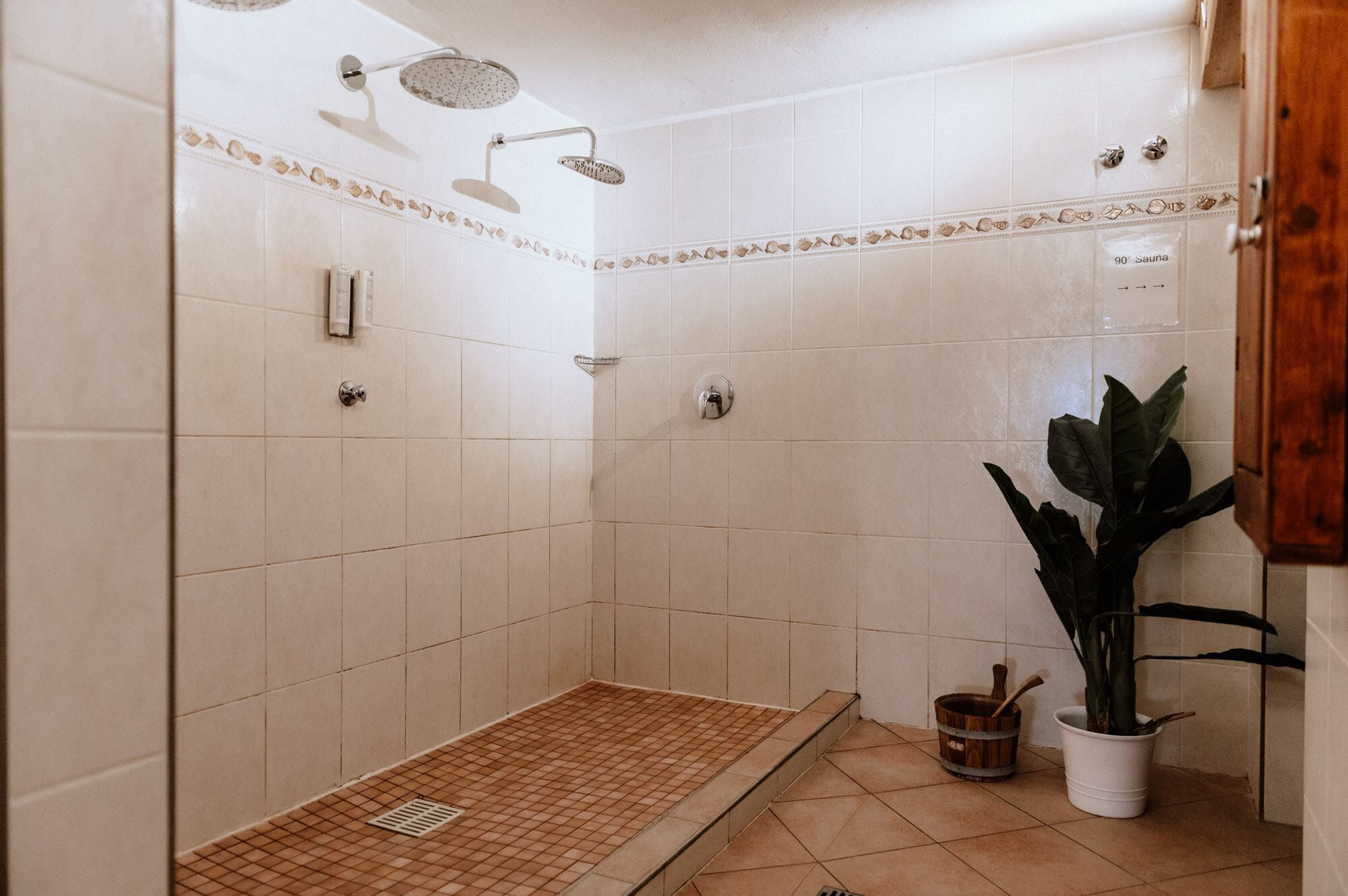 Et bruseområde med flisegulv, brusehoved og et skilt, der angiver en sauna.