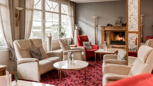 Un salón acogedor con chimenea, asientos cómodos y una alfombra estampada.