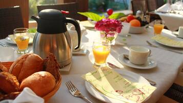 A breakfast table with a coffee pot, bread, fruit, and a menu.