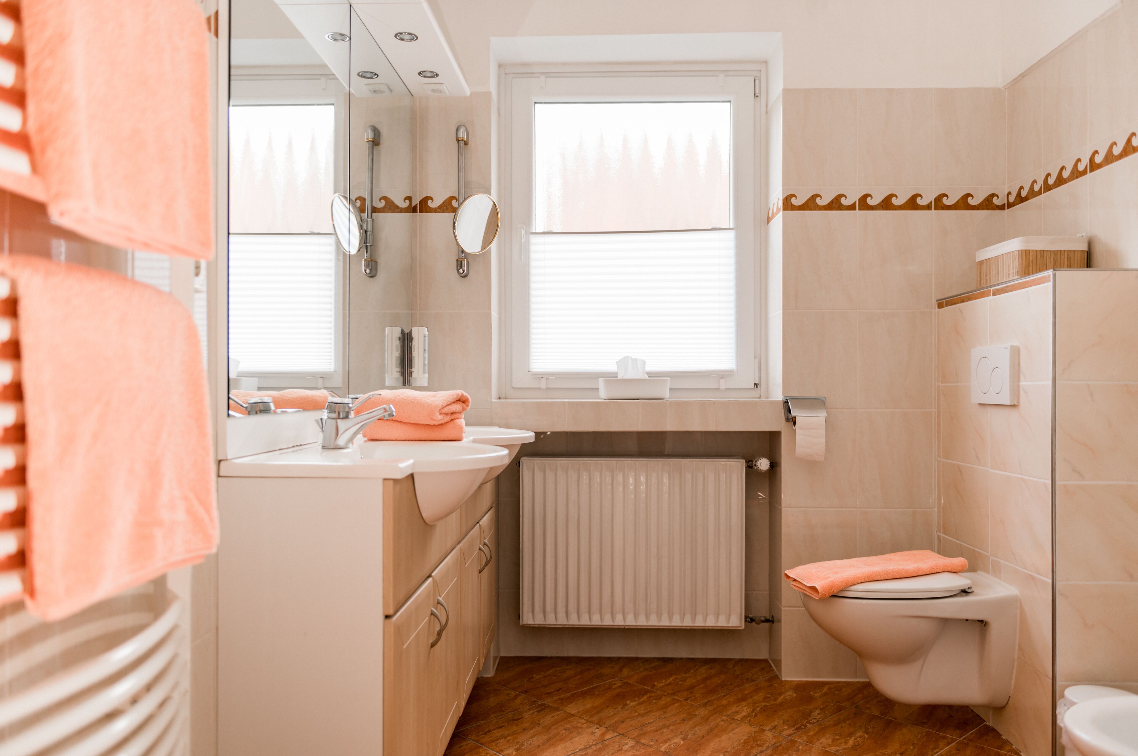 Ein modernes Badezimmer mit Waschbecken, Spiegel, Toilette und Fenster.