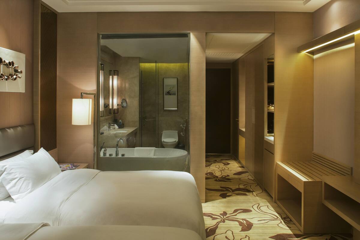Una habitación de hotel con una cama grande, un baño con bañera y un vestidor.