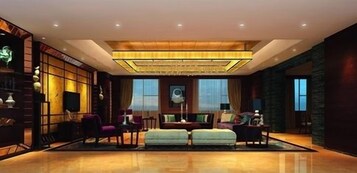 A spacious hotel lobby with a large seating area, a television, and a decorative ceiling.