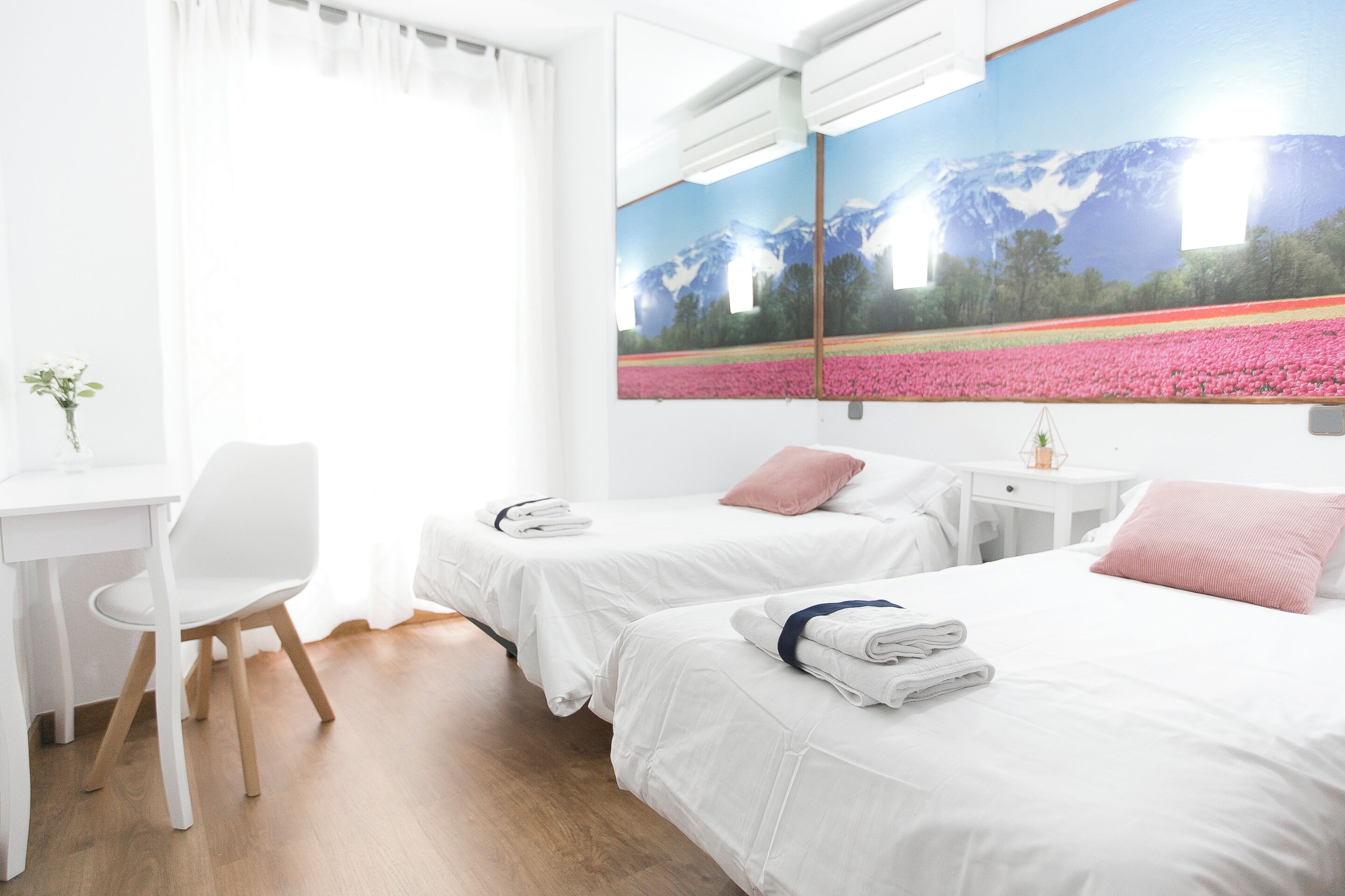 A hotel room with two beds, a desk, and a chair.