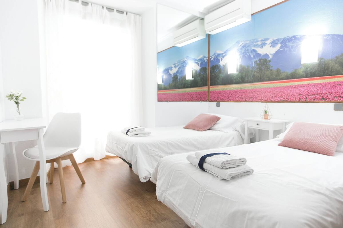 Habitación de hotel con dos camas, un escritorio y una silla.