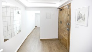 A hallway with a wooden door, a tiled wall, and a framed picture.