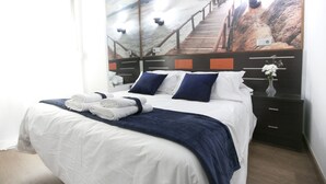 A neatly made bed with white and navy bedding, a dark blue throw blanket, and folded towels. - CH La Bañezana (Madrid)