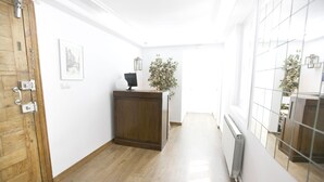 A hallway with a wooden door, a radiator, a potted plant, and a framed picture on the wall.