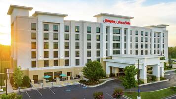 A Hampton Inn & Suites hotel with a modern design, featuring a large parking lot and a welcoming entrance.