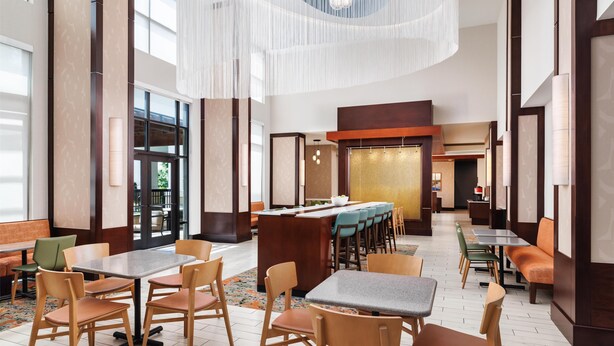 A spacious hotel lobby with multiple seating areas, including tables and chairs, and a central counter. - Hampton Inn & Suites Chattanooga/Hamilton Place (Chattanooga)