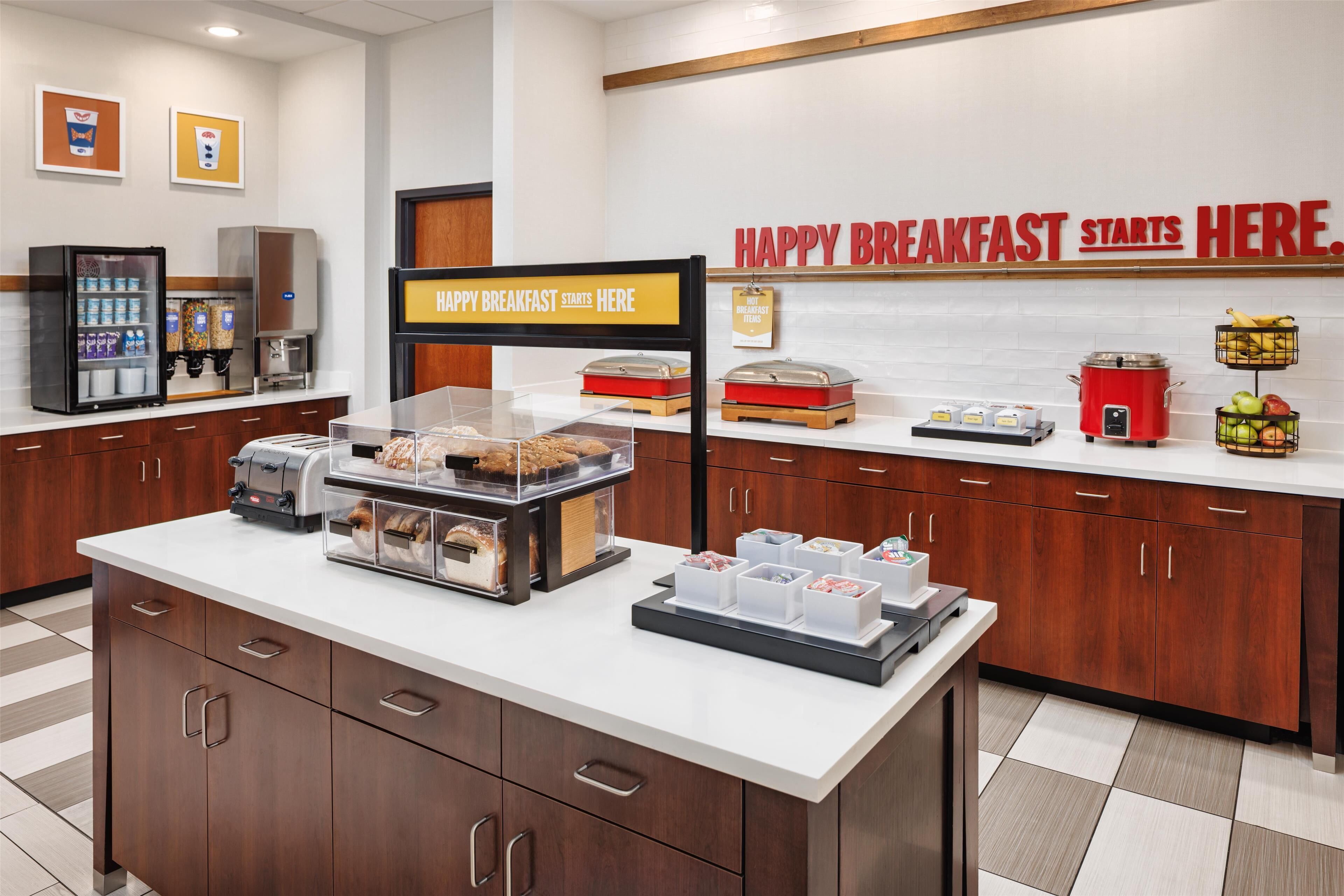 A breakfast buffet area with various food items and a sign that reads "HAPPY BREAKFAST STARTS HERE."