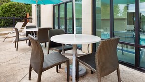An outdoor patio with wicker chairs, a round table, and a large umbrella. - Hampton Inn & Suites Chattanooga/Hamilton Place (Chattanooga)