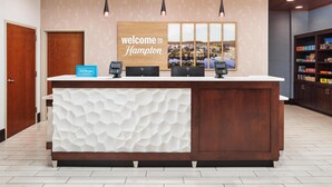 A reception desk with a 'Welcome to Hampton' sign, a 'Hilton Honors' sign, and a view of the cityscape through the window. - Hampton Inn & Suites Chattanooga/Hamilton Place (Chattanooga)