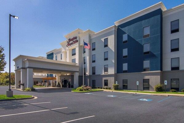 A Hampton Inn hotel with a modern exterior, a welcoming entrance, and designated parking spaces including a handicapped spot.