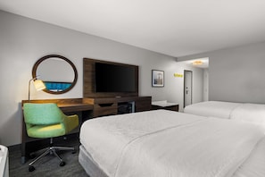 A hotel room with a bed, a desk with a chair, a television, and a mirror.