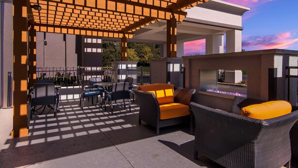 An outdoor patio area with wicker furniture, a fire feature, and a pergola structure. - Hampton Inn & Suites Schererville (Schererville)