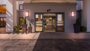 A hotel entrance with a modern design, featuring a glass door and a welcoming outdoor area with potted plants. - Hampton Inn & Suites Schererville (Schererville)