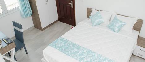 A bedroom with a bed, a desk, and a chair.