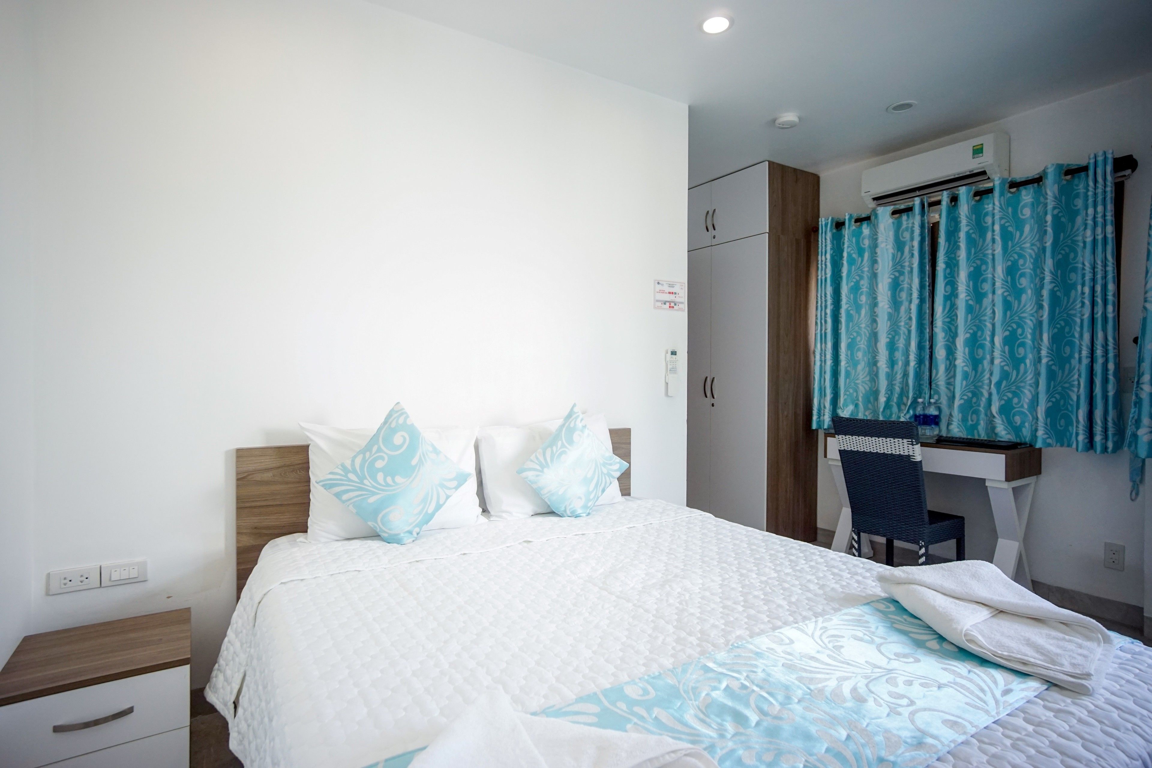 Een slaapkamer met een bed, een bureau en een stoel.
