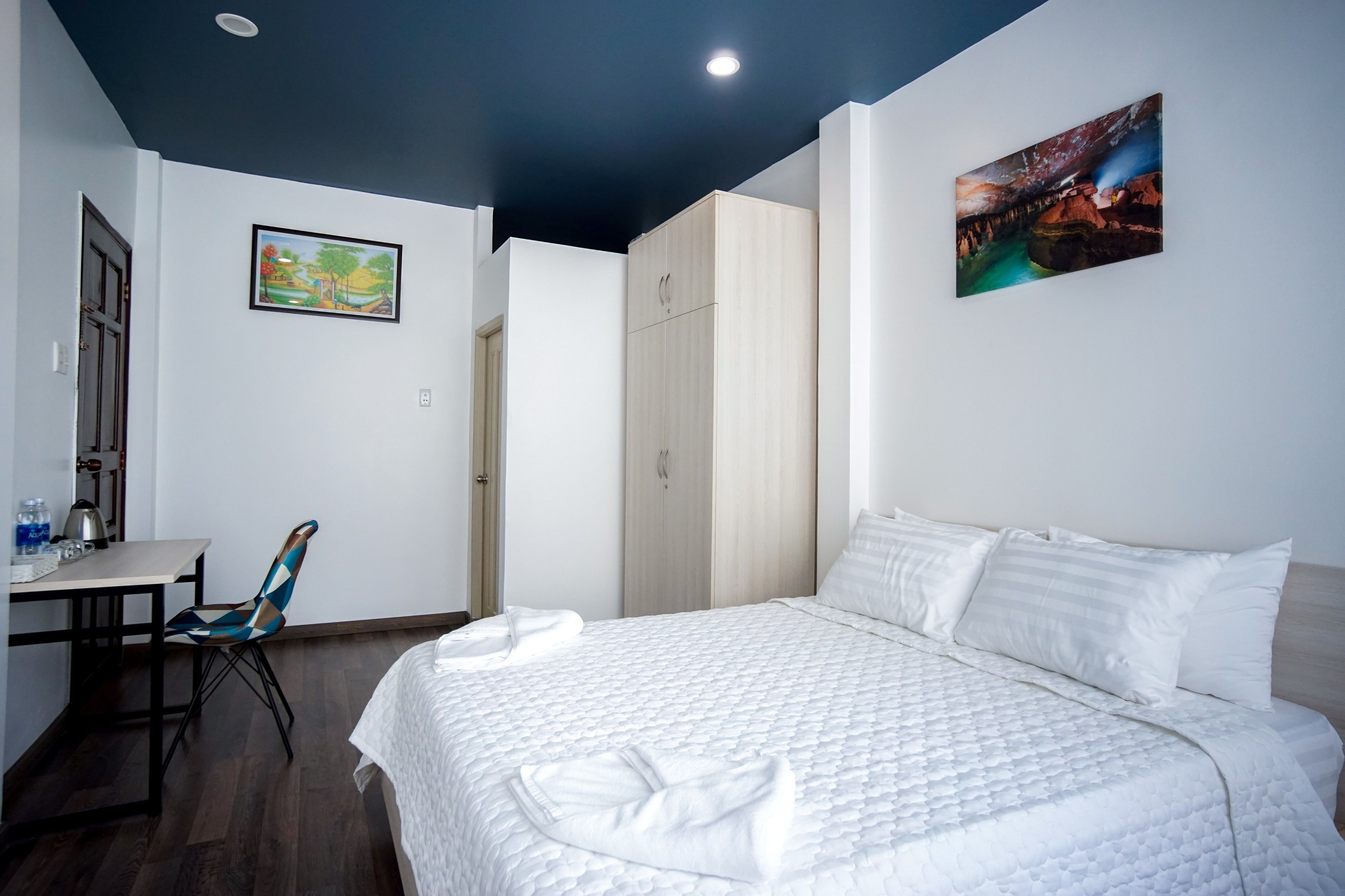 A hotel room with a bed, a desk, a chair, and a wardrobe.