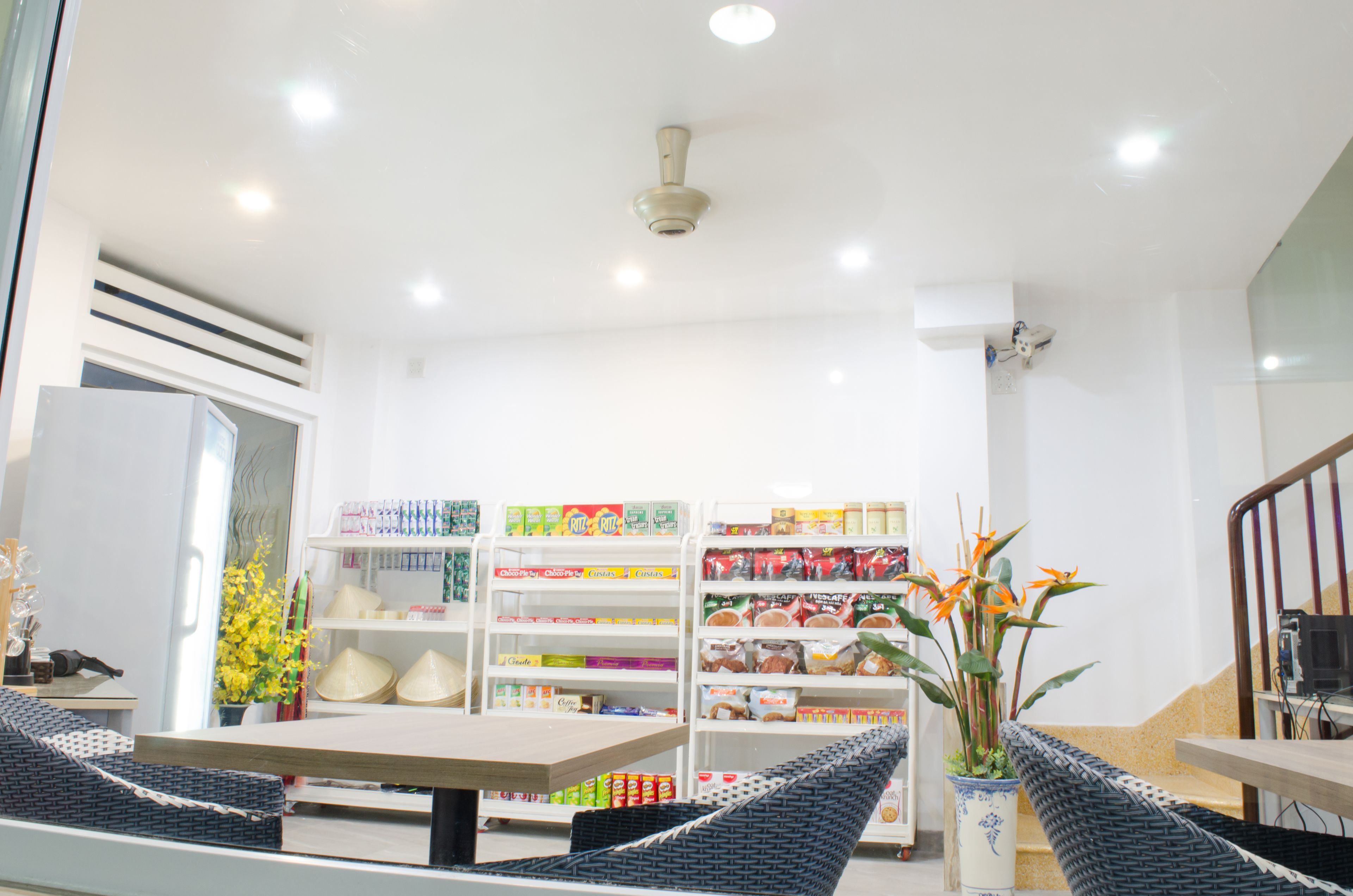 A hotel lobby with a reception desk, seating area, and a variety of food and beverage products on shelves.