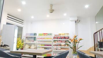 A hotel lobby with a reception desk, seating area, and a variety of food and beverage products on shelves.