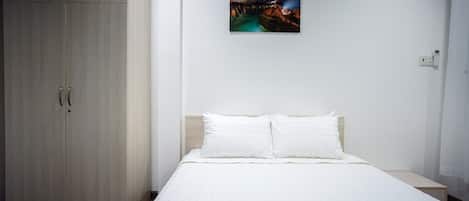 Una camera d'albergo con un letto, un armadio, un quadro appeso al muro e un condizionatore d'aria.