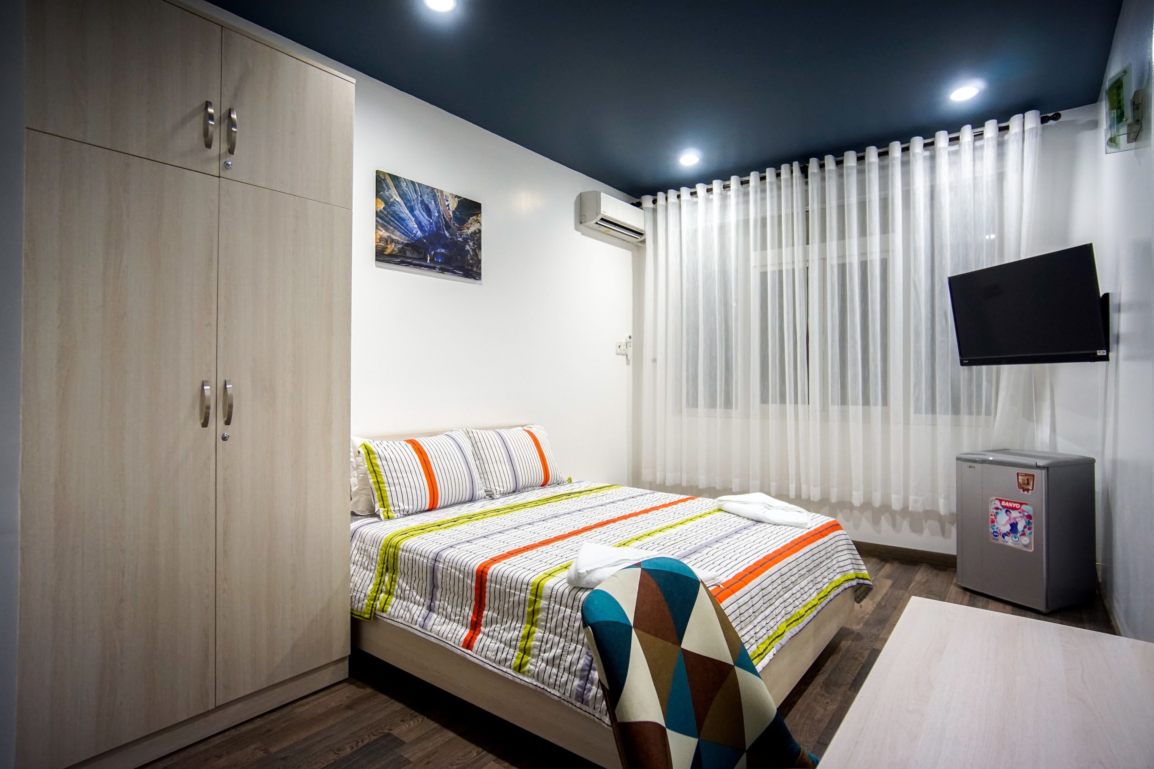 Ein Schlafzimmer mit Bett, Kleiderschrank, Fernseher und Klimaanlage.