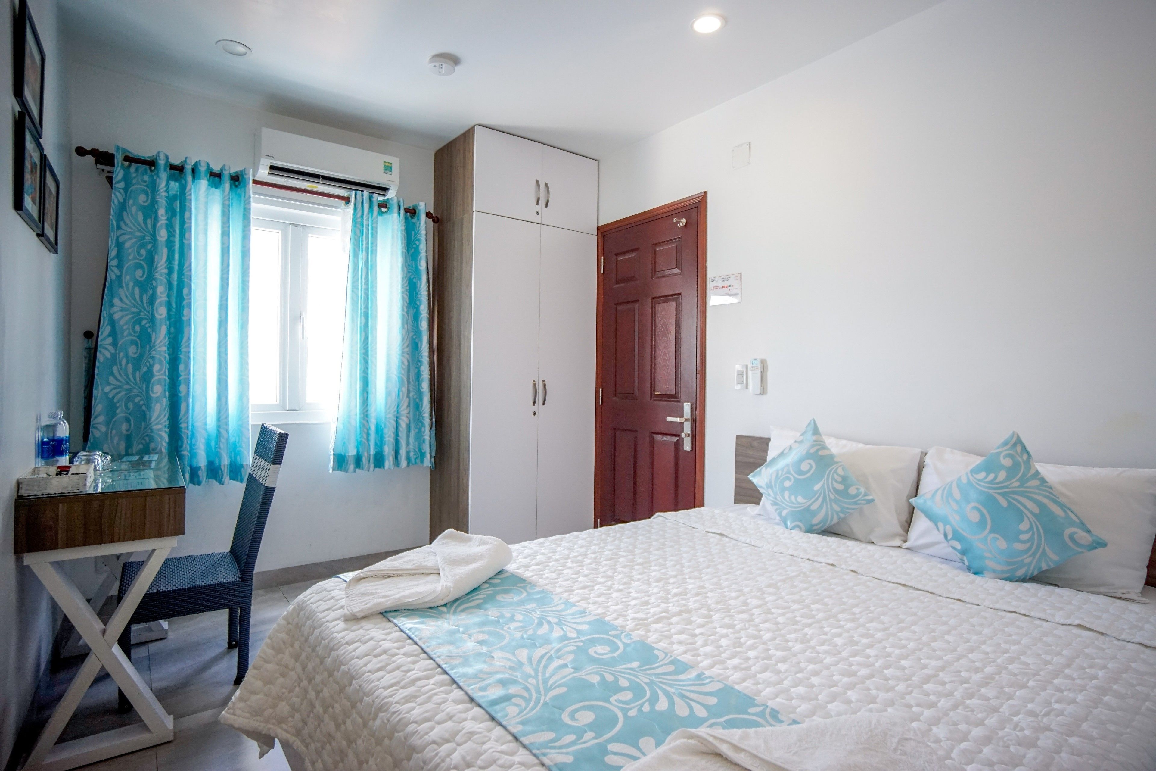 Un dormitorio con cama, escritorio, silla, armario y puerta.