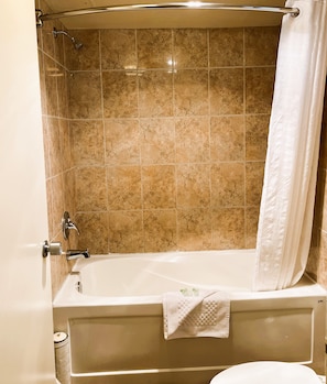 Un baño con bañera, ducha y paredes de azulejos.