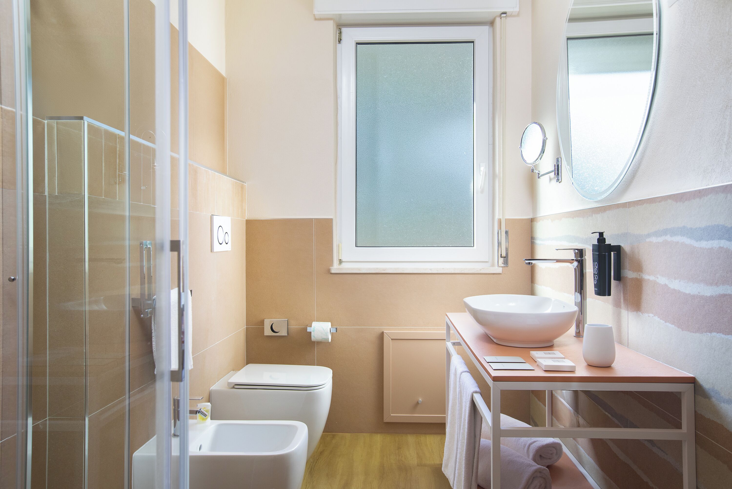 Un baño moderno con cabina de ducha de vidrio, un lavabo blanco y un espejo sobre el mueble.