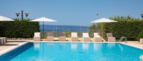 Una piscina al aire libre de temporada, sombrillas