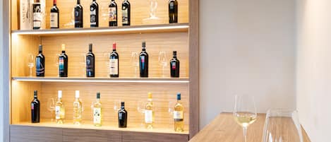A modern dining area with a wooden table, two orange chairs, and a wine rack with various bottles and glasses.