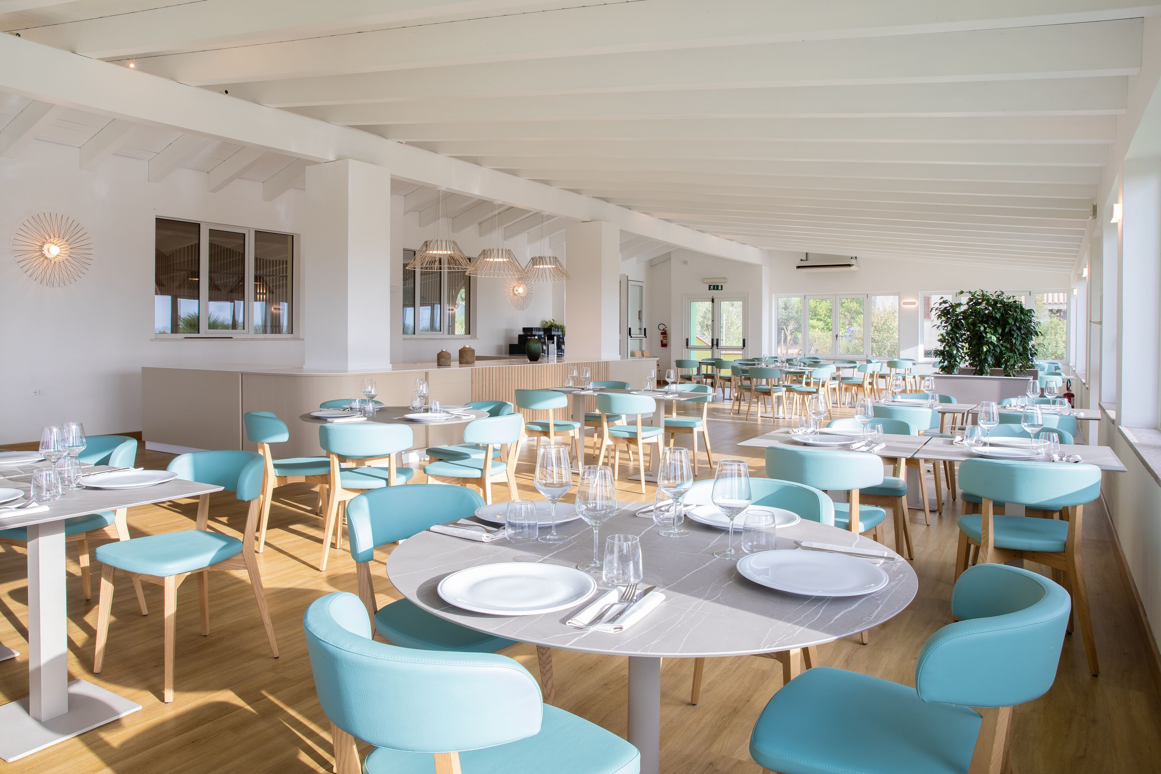 En rummelig spiseplads med runde borde, blå stole og et moderne interiørdesign.