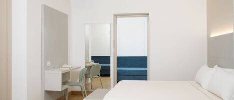 A modern hotel room with a bed, a desk, and a chair.