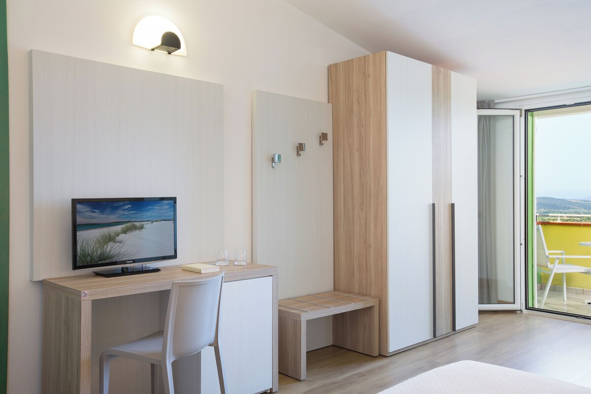 Una habitación moderna con escritorio, silla y televisión mostrando una escena de playa.