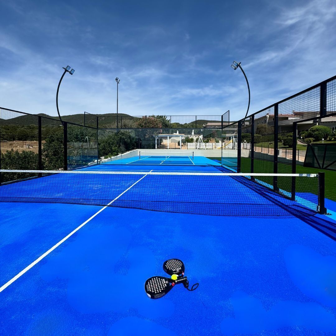 A tennis court with a net, two tennis rackets, and floodlights.