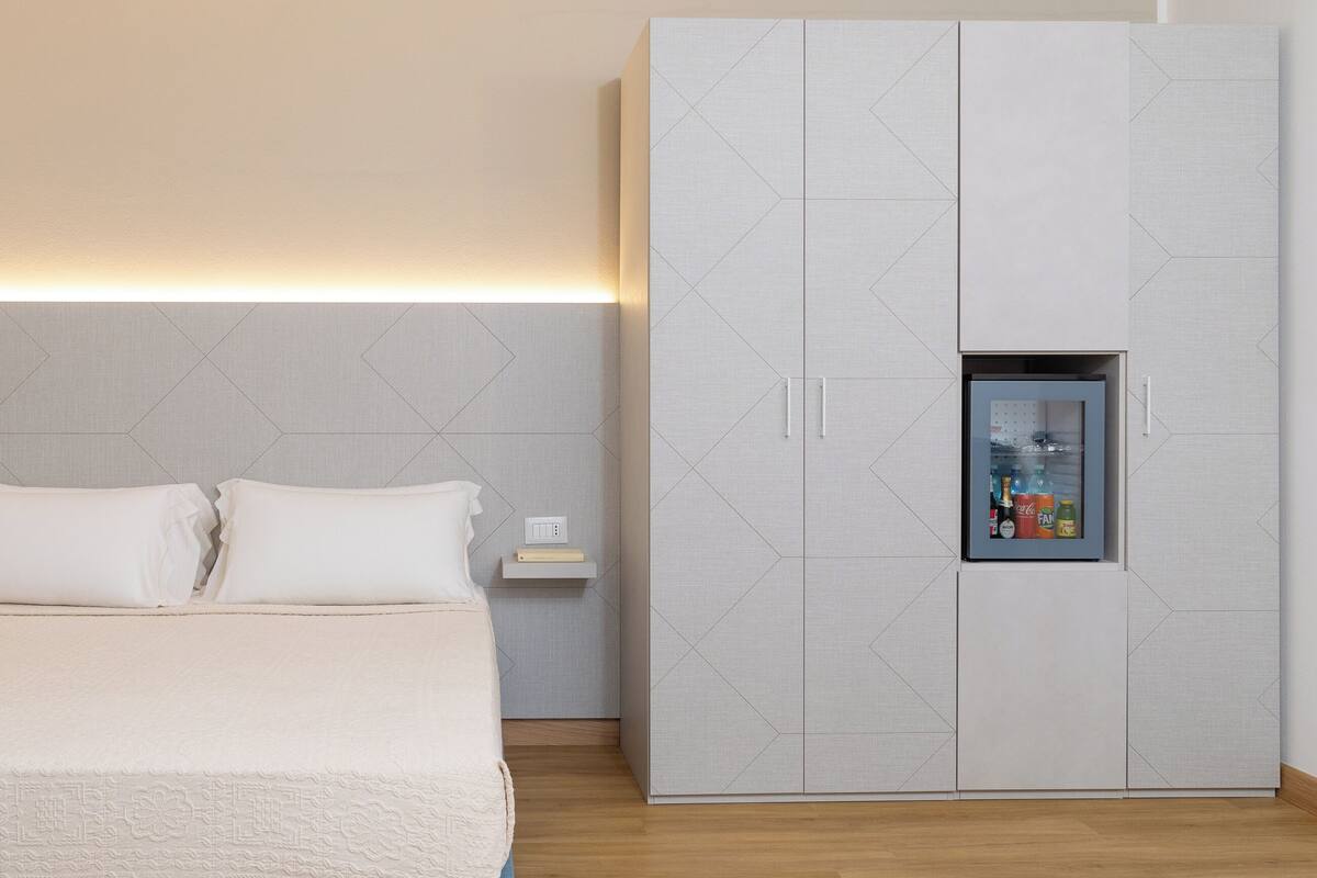 Ein Schlafzimmer mit einem Bett, einem Kleiderschrank und einem Regal mit einer Uhr und Flaschen.