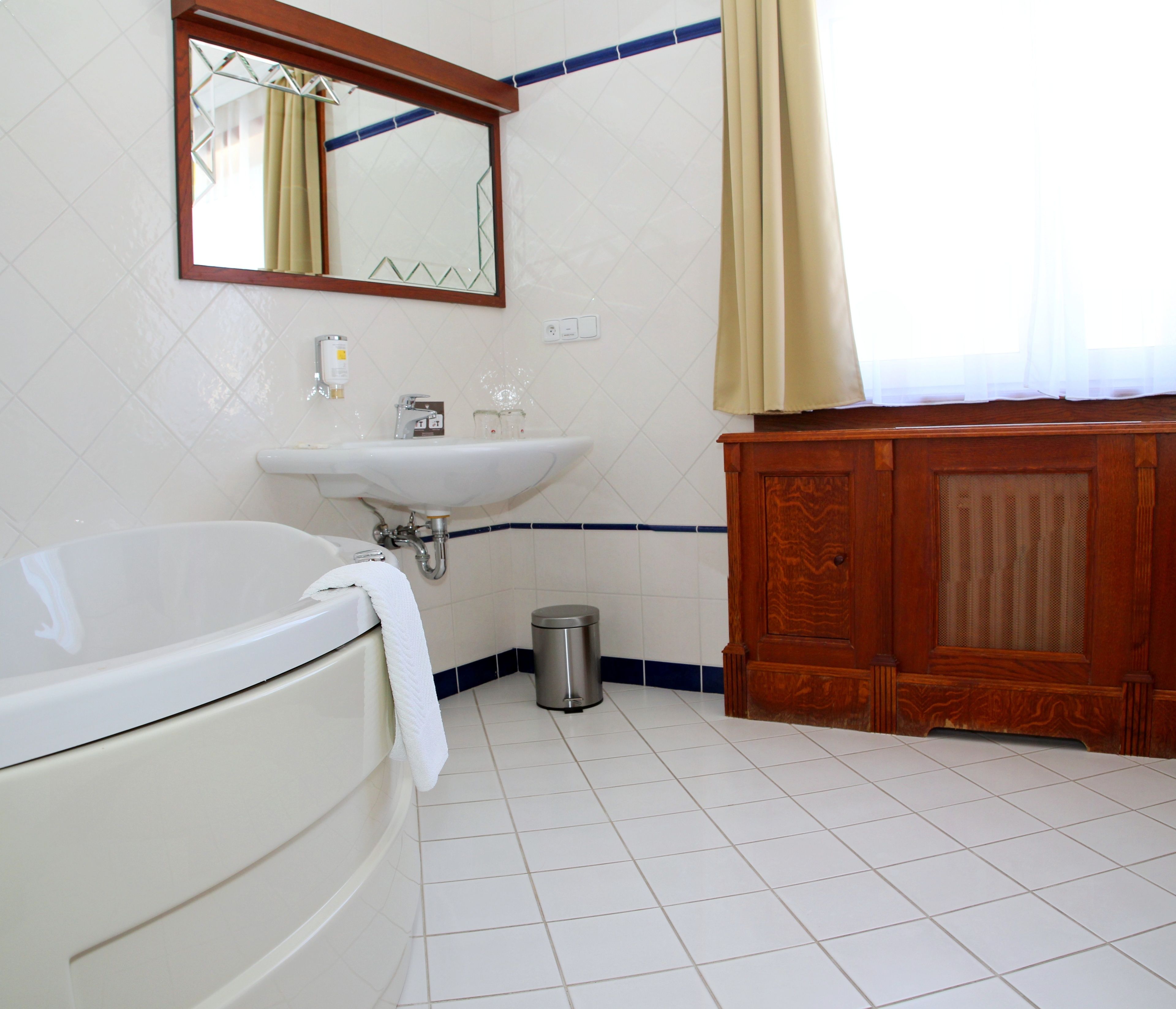 Een badkamer met een wit bad, een wastafel en een houten kastje.