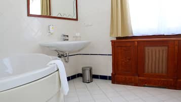 Een badkamer met een wit bad, een wastafel en een houten kastje.