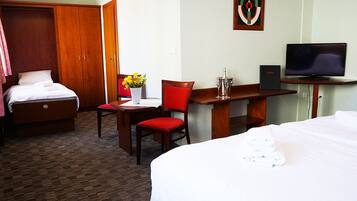 Une chambre d’hôtel avec un lit, un bureau et une chaise, une télévision et un tableau au mur.